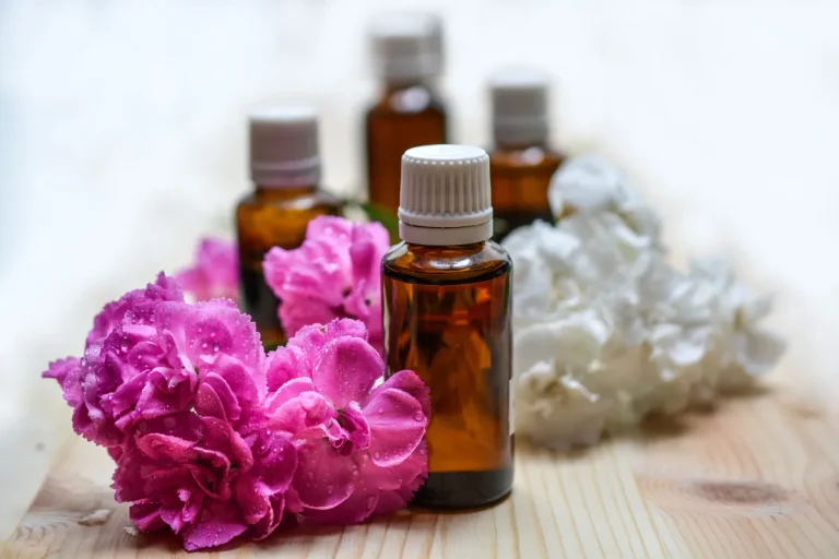 Amber bottles of Balinese aromatherapy oil beside frangipani flowers and sea salt