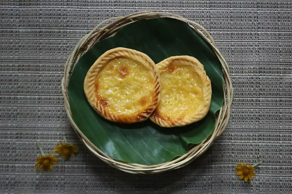 Two Balinese pie susu tarts served on a banana leaf
