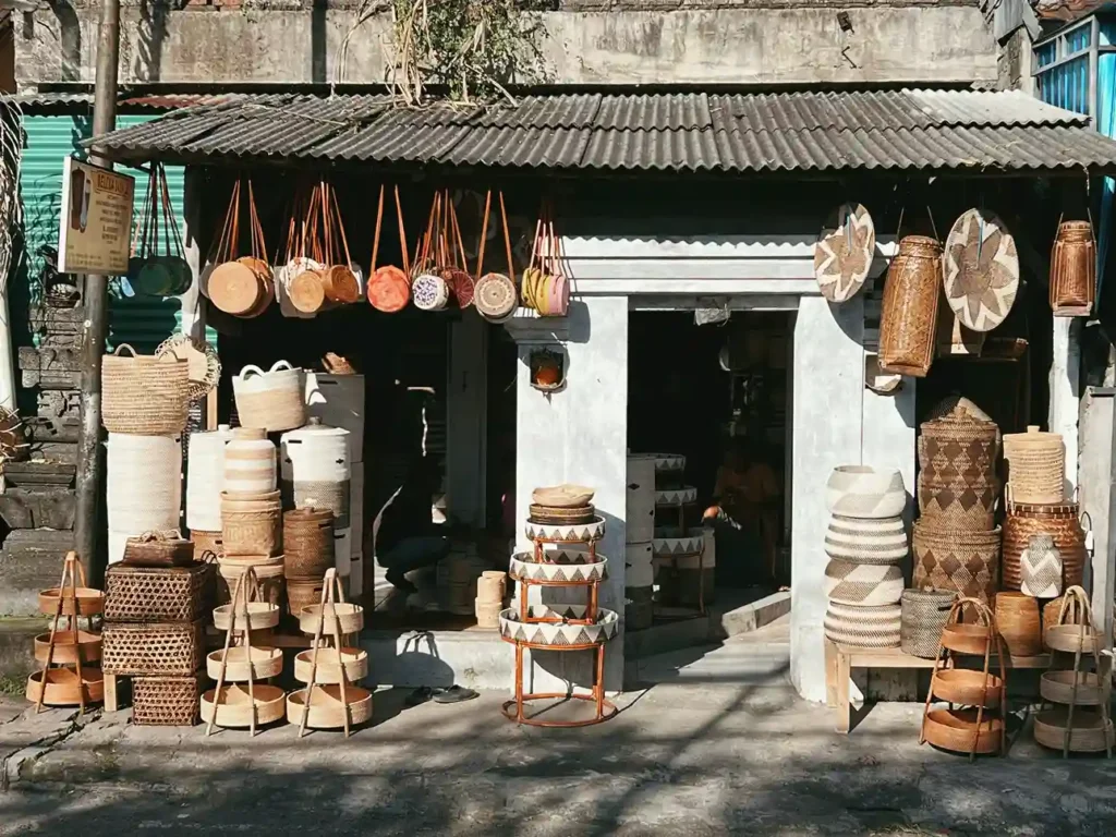 Woven rattan bags, baskets and platters stacked outside a Balinese basketware workshop
