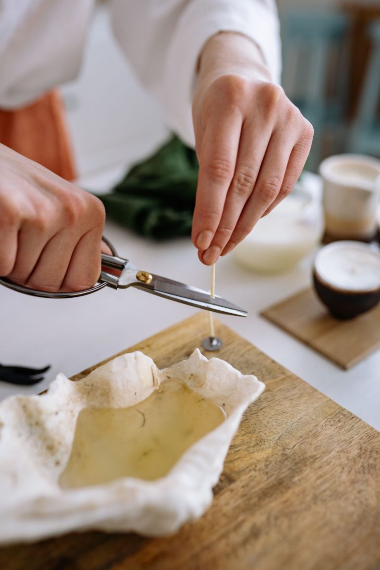 Hands trimming a block of handmade botanical soap on a wooden board
