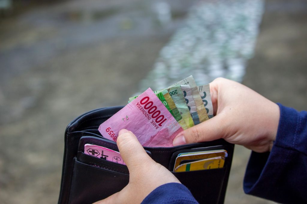 Hands counting Indonesian rupiah banknotes from a wallet