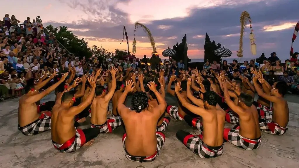 Kecak dancers in a ring at sunset in a clifftop temple courtyard